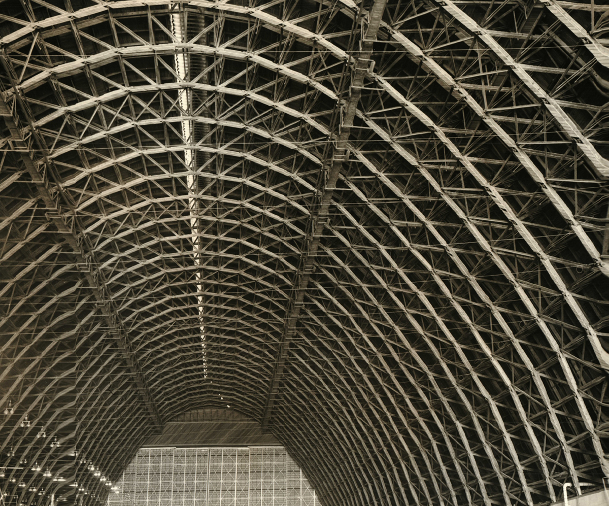 An interior view down the length of Hangar 3 looking up at its wood parabolic arch trusses.