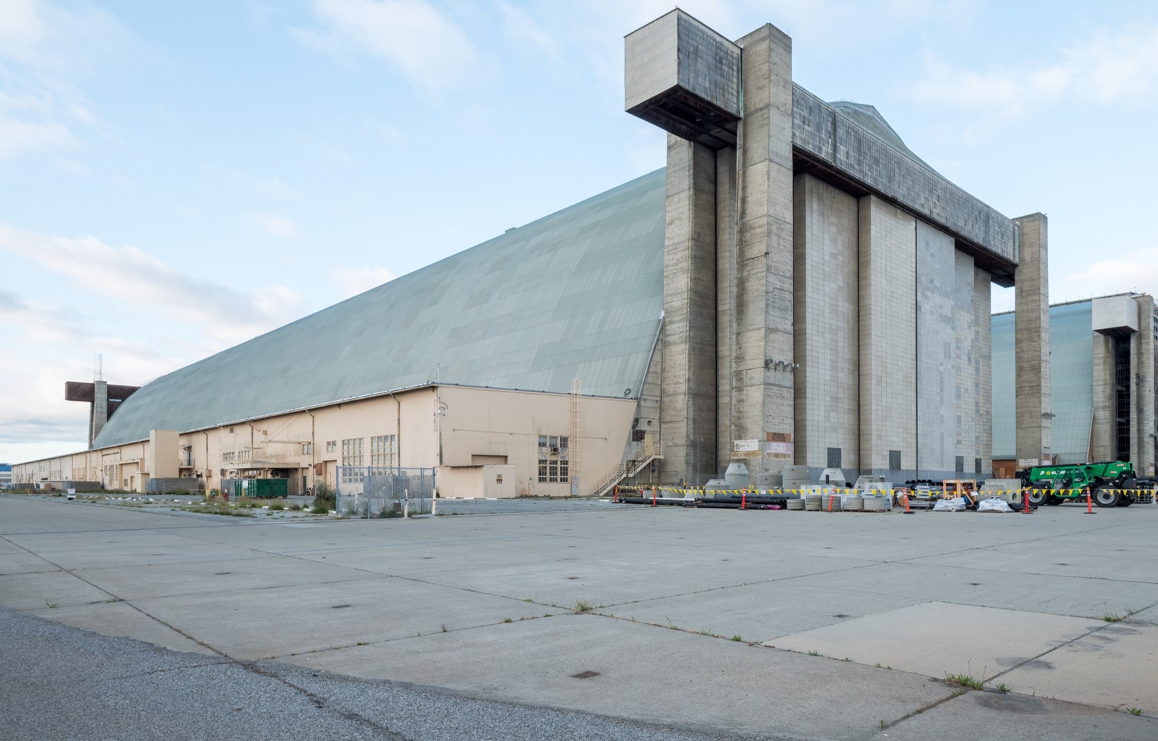 A wide view of the exterior corner of Hangar 3 with its doors closed and the two-story annex building along its long façade.