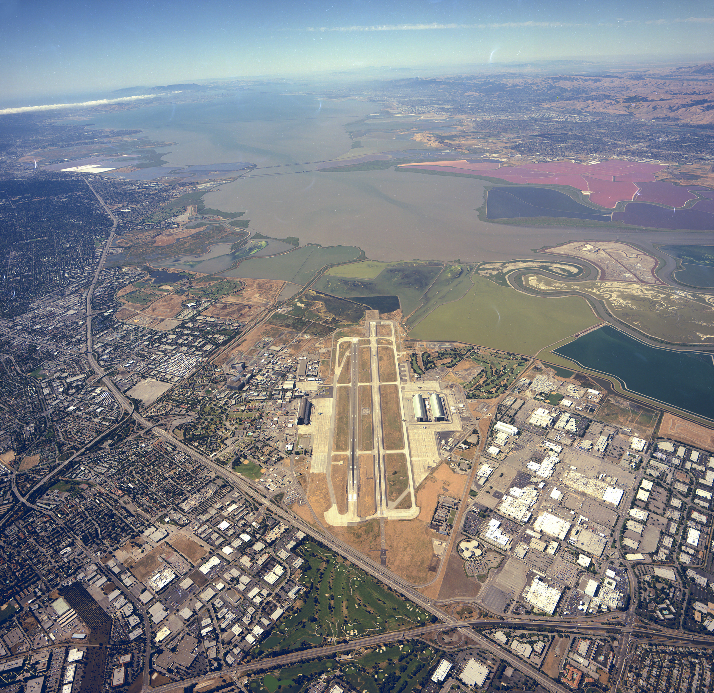 An aerial view of Moffett Field, its adjacent wetlands, the San Francisco Bay and nearby landscapes, and the cities of Mountain View and Sunnyvale.